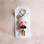 Keychain with character design on a white card against a beige background