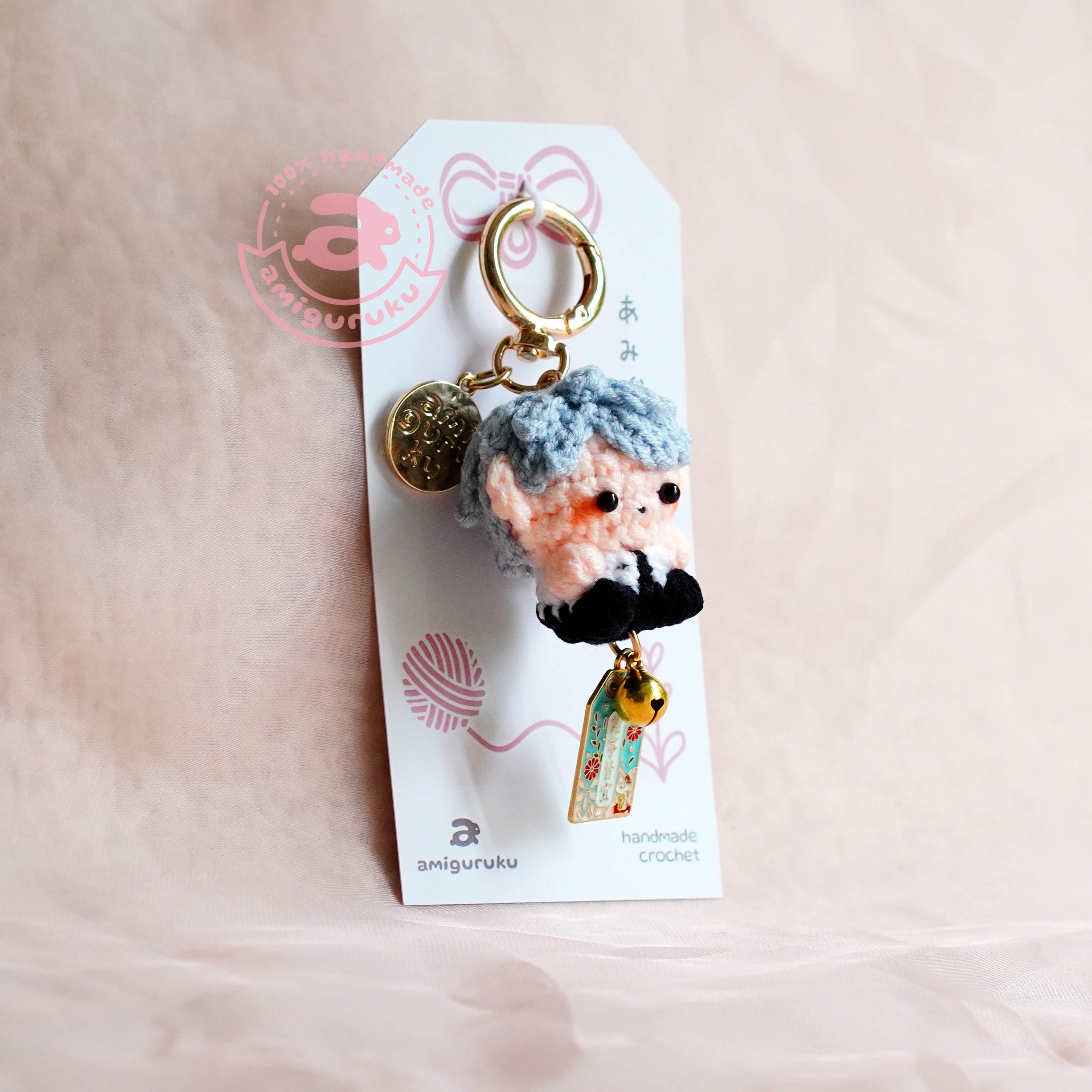 Keychain with a plush character on a white card against a beige background