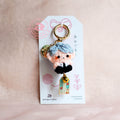 Keychain with a character on a white card against a beige background