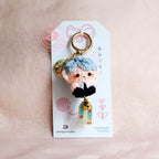 Keychain with a character on a white card against a beige background